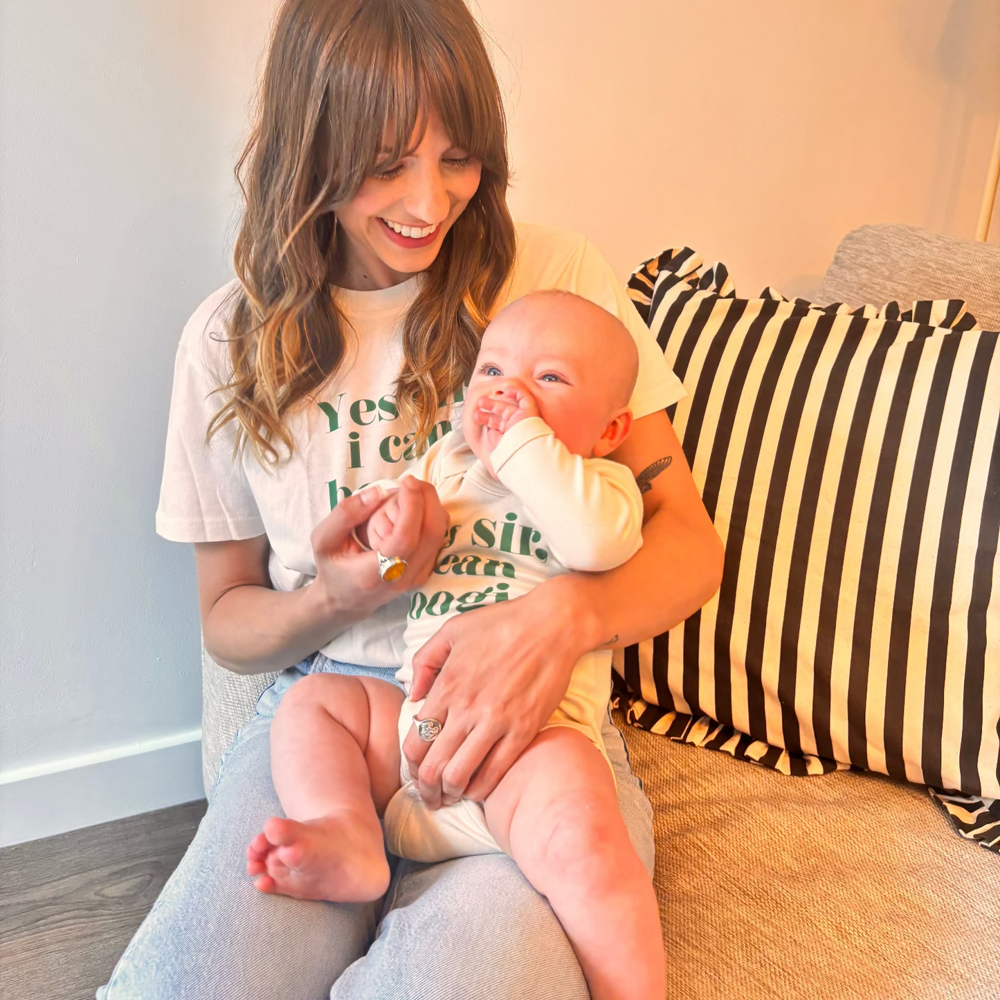 Woman holding a baby on a couch with a striped pillow in the background