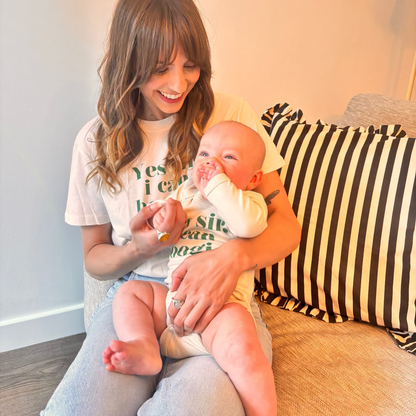 Woman holding a baby on a couch with a striped pillow in the background