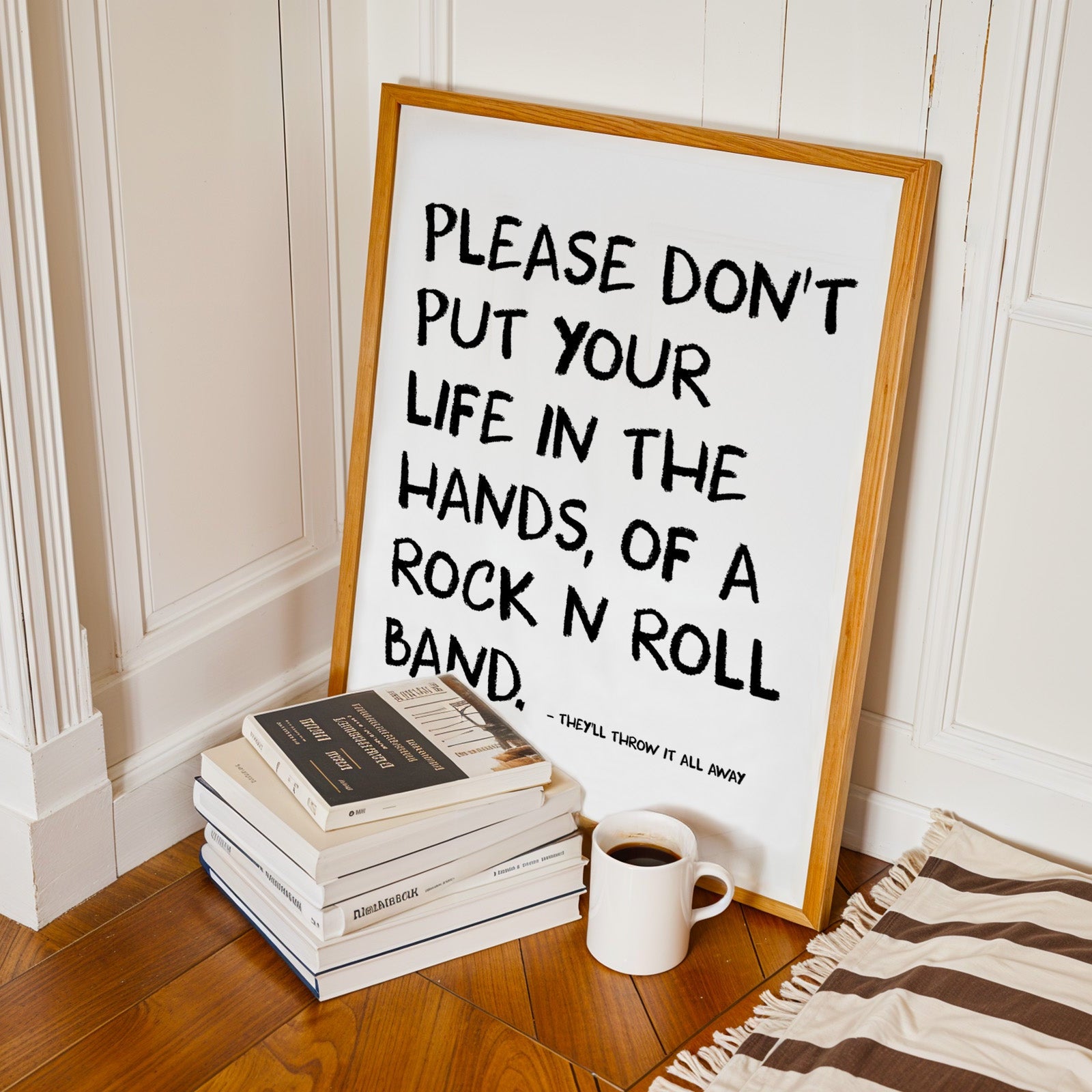 Framed poster with motivational quote on a stack of books with a cup of coffee on a wooden floor.