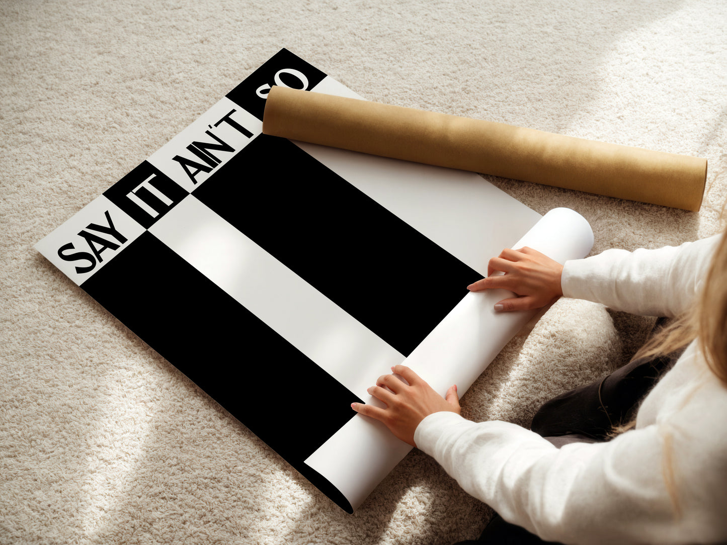 Person unrolling a black and white striped poster with text on a carpeted floor.